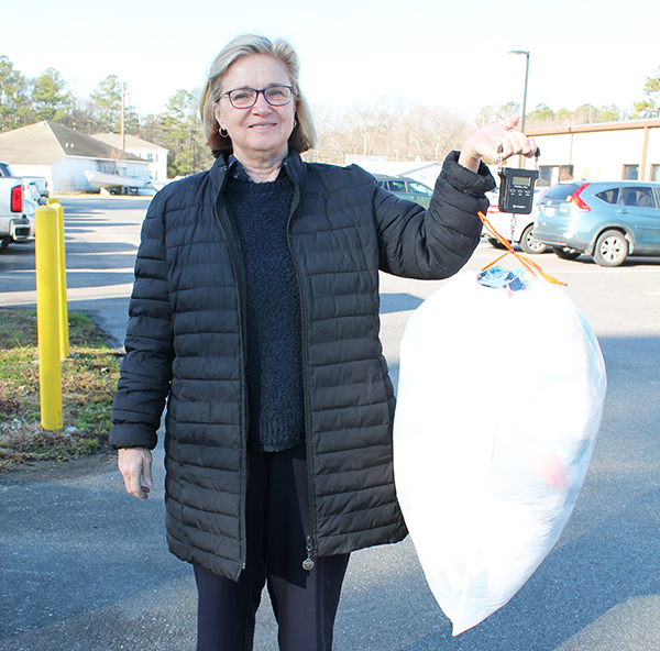 Sheila Crowley measures a bag of recyclable plastic that Mathews Family YMCA members and staff have collected in order to earn a bench to place outdoors at the Y. Five hundred pounds of plastic is needed; 339 pounds have been collected. The bag weighed 5.94 pounds. The deadline is March 15. Photo by Sherry Hamilton