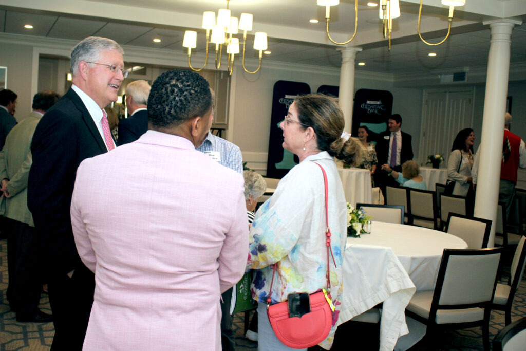 Chesapeake Financial Shares, Inc., holding company of Chesapeake Bank and Chesapeake Wealth Management, held its 125th anniversary shareholders meeting on Friday afternoon at Indian Creek Yacht & Country Club, Kilmarnock. Along with the numbers, Chairman, President and CEO Jeffrey M. Szyperski (in photo below at left, chatting with some of those gathered), presented banking industry trends and insights. In 2025, CFS delivered strong financial performance driven by disciplined strategy and long‑term positioning, a release stated. Fourth quarter earnings totaled $6.45 million, more than double the prior year, while full‑year earnings reached $10 million. Total assets grew to $1.67 billion, loan growth exceeded targets, asset quality remained strong, and diversified non‑interest income divisions contributed meaningfully to results.